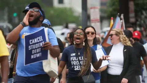 Reuters People holding 'cancel student debt now' signs