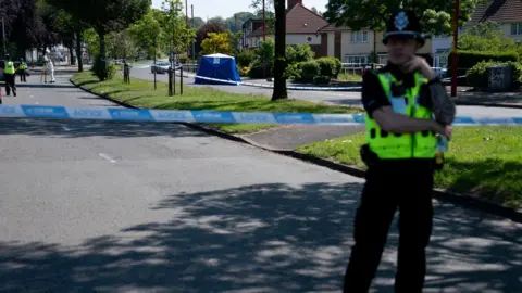PA Media A police officer stands near the scene on College Road, Kingstanding, north of Birmingham