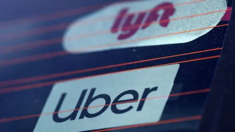 Reuters Uber and Lyft signs in a car window