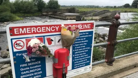 Flowers attached to an emergency sign at the accident scene