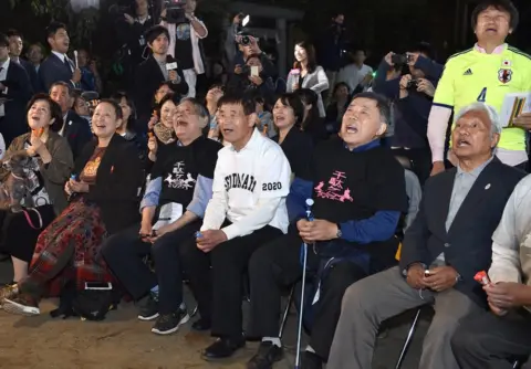 AFP/Getty Images Fans of Japanese novelist Haruki Murakami react when the Swedish Academy awarded the Nobel prize for literature to US musician Bob Dylan at a shrine in Tokyo on 13 October 2016.