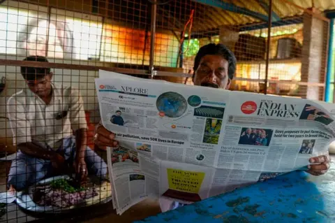 AFP A man reads a newspaper featuring front-page news on US President Joe Biden and Vice President Kamala Harris at her ancestral village of Thulasendrapuram in the southern Indian state of Tamil Nadu on January 21, 2021