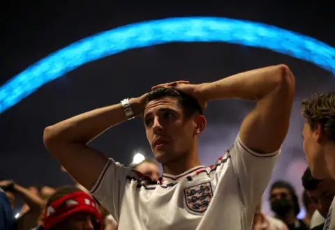 Chloe Knott / Getty Images An England fan puts his hand on his head outside Wembley Stadium