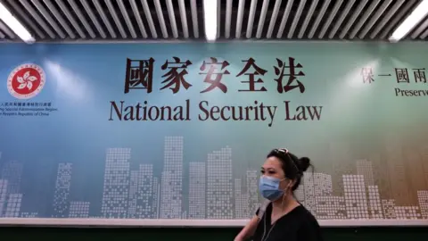 Getty Images A woman walks past a poster for the National Security Law in Hong Kong on July 28, 2020