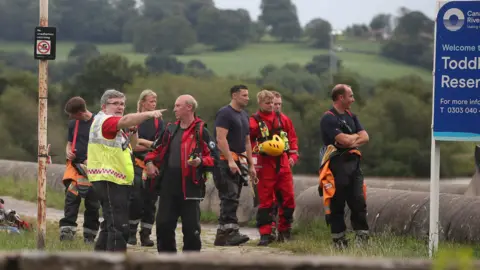 PA Media Rescuers organise themselves at the reservoir edge