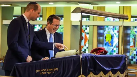 PA Media Rabbi Daniel Epstein shows the Prince of Wales a 17th-century Torah scroll as he visits the Western Marble Arch Synagogue in London