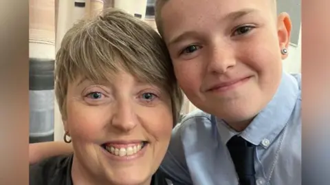 A selfie of Jodie and her son. Jodie has short blonde hair. Her son has his arm around her