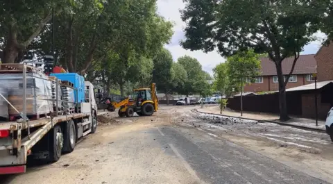 A tractor and a truck seen on a road covered in mud.