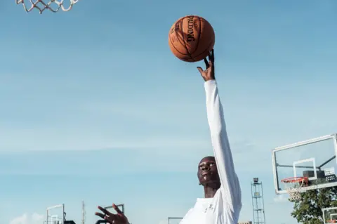 Guy Peterson/AFP Tasha, 17, throws a basketball at the Luol Deng Basketball Academy in Juba, South Sudan - Monday 12 June 2023