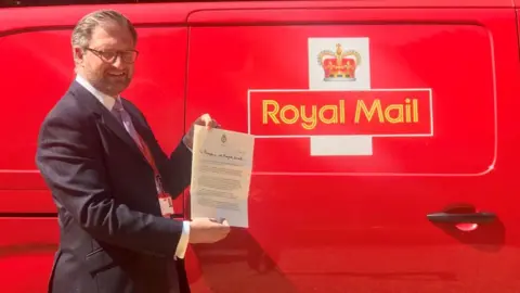 Clarence House/PA Wire Royal Mail director of public affairs David Gold holds up the letter