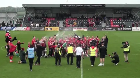 BBC Truro City Football Club players on the pitch at Truro Community Stadium. The players are celebrating after the win.