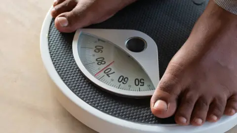 Getty Images Male on the weight scale for check weight.