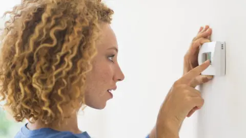 Getty Images Woman checking thermostat