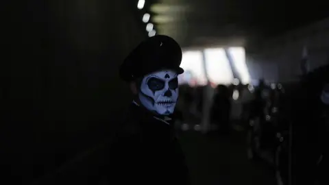 Getty Images A man dressed as a dead chauffeur skeleton escorts parade through an underpass