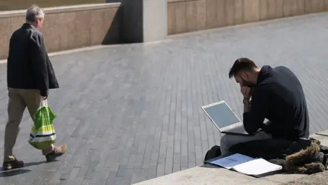 PA Media Man working on laptop by the River Thames in London