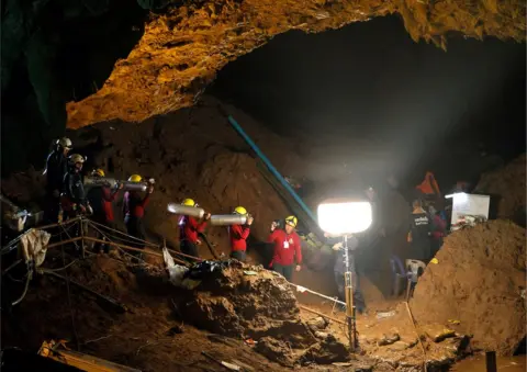 EPA Thai officials carry oxygen tanks through a cave complex at the Tham Luang cave