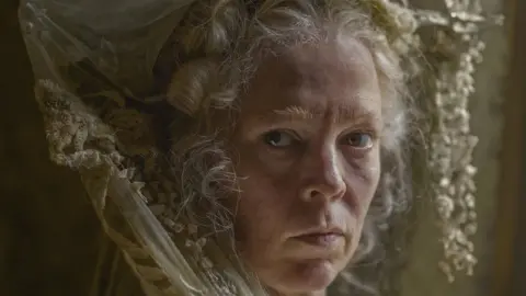 Olivia Colman dressed as Miss Havisham, in a white wig with an elaborate head garment