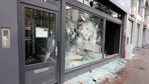 AFP/ Getty Images shop window riddled with holes, broken glass on the ground