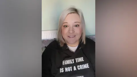 Supplied A selfie photo of a smiling woman in a campaign hoodie which says 'Family time is not a crime'