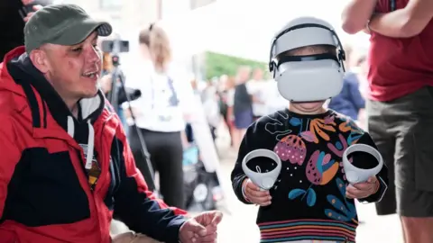 Richard Dawson Child using a VR headset while a man looks on.