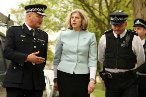 Getty Images Theresa May with two police officers