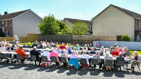 Pacemaker Crowd of people seated at table for street party