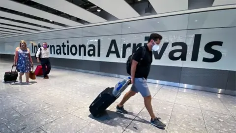 PA Media People arriving at Heathrow airport wearing face masks