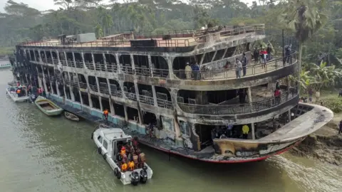 EPA Firefighters and coast guard personnel at the scene of a passenger ferry that caught fire near the southern rural town of Jhalakathi, south of Dhaka in Bangladesh, 24 December 2021