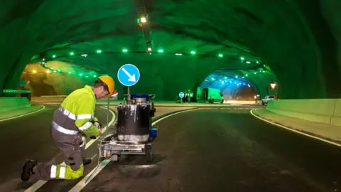 Estunlar.fo A worker paints road markings inside the tunnel