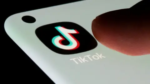 Reuters Thumb about to press TikTok app logo on a mobile phone screen.