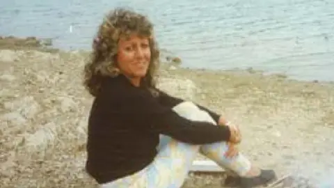 Archive image of Marina Koppel sat on a beach by a small barbeque