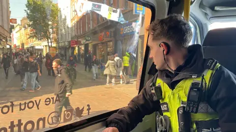 A police officer keeps watch from a van patrolling the city centre