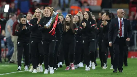 Reuters Liverpool's Rachel Furness holds the trophy on the pitch at Anfield after winning the Women's Championship