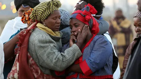 Getty Images Women mourn as family members of the 34 people who died when police opened fire on strikers at the Lonmin platinum mine north west of Johannesburg on August 16, 2013 gather at the scene of the bloody shooting to cleanse the ground