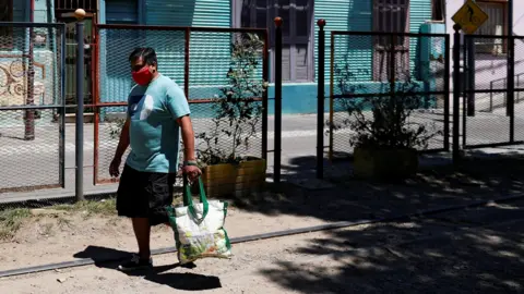 a man in a mask carries a shopping bag