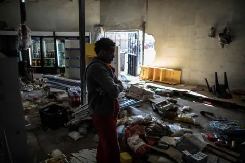 AFP The Ethiopian owner of a looted grocery store in Soweto, Johannesburg, stands in his ransacked shop