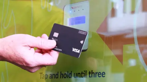 Harrogate Borough Council Hand holding a debit card to a contactless payment terminal