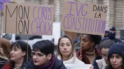 AFP Placards reading "My body my choice" (L) and "Abortion in the Constitution" are seen during a rally to call for the constitutionalisation of the right to abortion outside the Senate in Paris, on February 01, 2023.