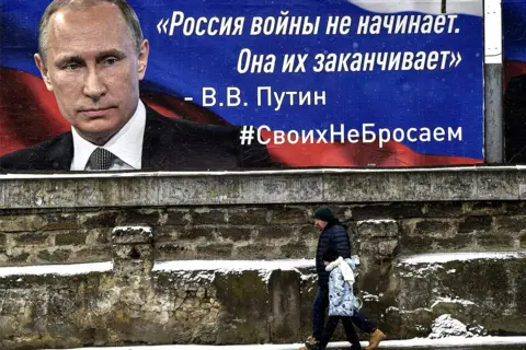 Rex Features People walk past a poster of Vladimir Putin reading "Russia does not start wars, it ends them," Simferopol, Crimea, 10 March 2022