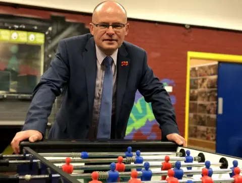 BBC Ian Levy at a football table with blue and red players at Cramlington Voluntary Youth Project
