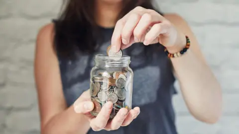 Woman holding glass jar with coins in it