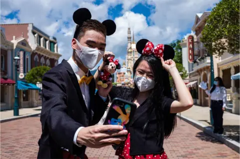 Anthony Wallace / AFP Visitors dressed in costumes take a selfie at Hong Kong's Disneyland