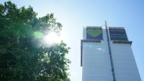 PA Media The tower today with a protective wrap showing green heart and the message "Forever in our hearts"