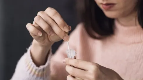 Getty Images Woman using lateral flow test
