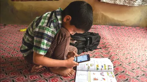 Getty Images A Kashmiri student listen to the lecture (voice) of his teacher during an online class via Zoom app as schools remain closed amid the fight against the COVID-19 outbreak in Kashmir.