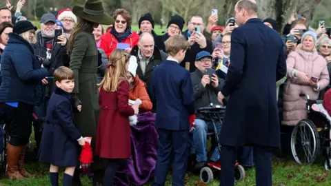 Reuters The Prince and Princess of Wales and their children greeting crowds at Sandringham