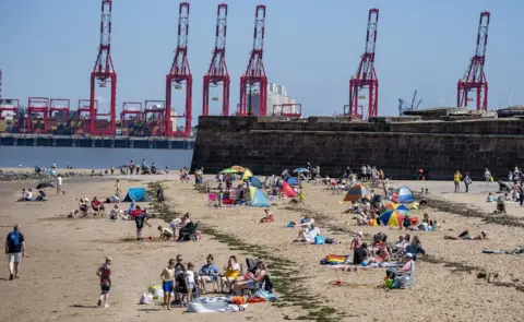 PA Media Sunbathers make the most of the mini heatwave in New Brighton, Wirral,