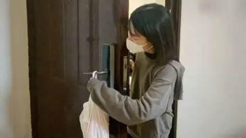 Meituan A woman takes delivery of food using contactless delivery