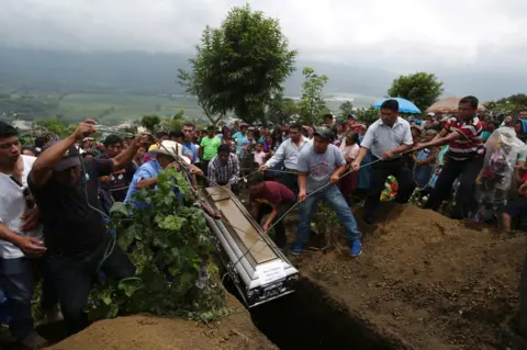Jose Cabezas / Reuters A coffin is lowered into the ground with ropes