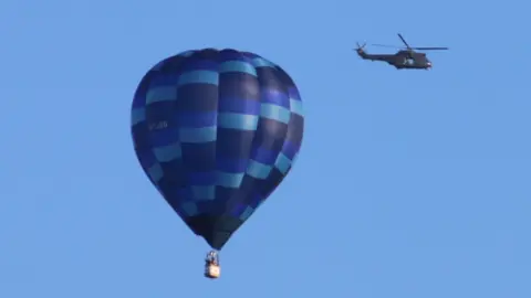 Christine Cook A hot air balloon and helicopter flying over Drayton